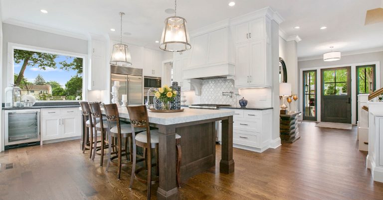 Modern kitchen with white cabinetry, dark wood island, pendant lighting, and hardwood floors in open floor plan home