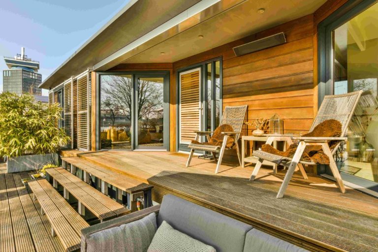 Modern wooden ADU with deck, outdoor seating, and large windows overlooking green landscape
