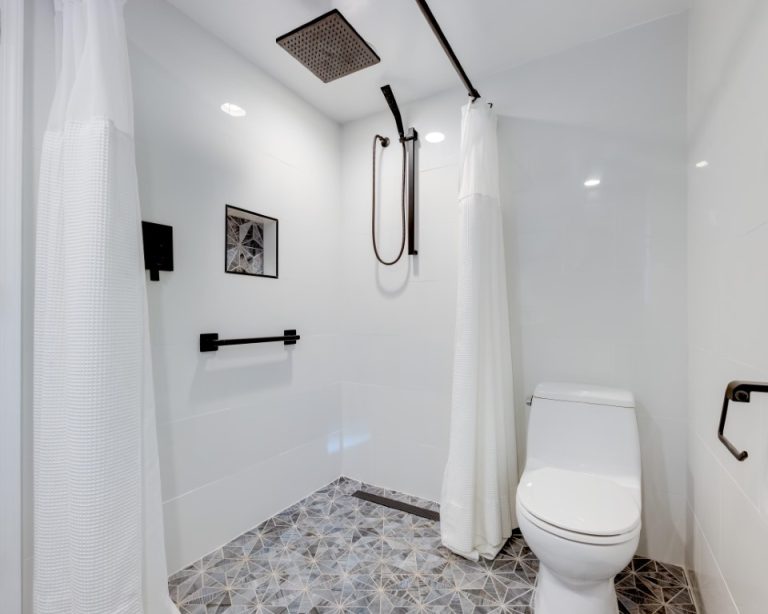Modern bathroom with walk-in shower, white subway tile walls, rainfall showerhead, toilet, and pebble floor