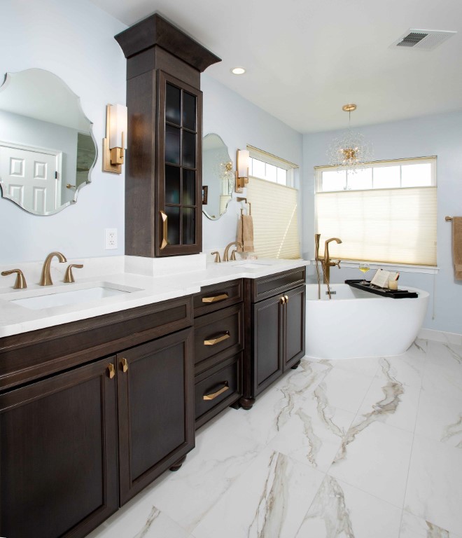Modern luxury bathroom with dark cabinetry, white marble countertops, dual vanity sinks, and large windows