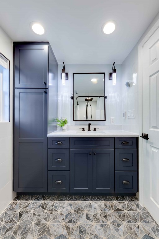 Modern bathroom vanity with dark blue cabinetry, double sink, and hexagonal tile flooring