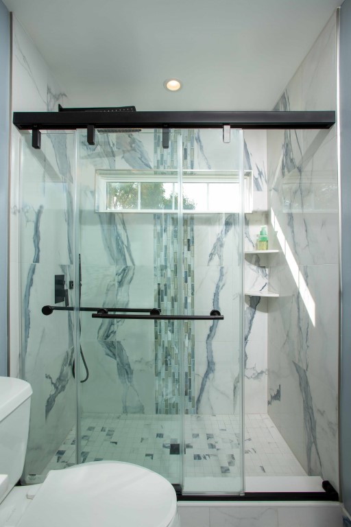 Modern bathroom shower enclosure with marble tile walls and black metal framing