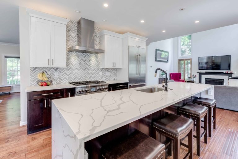 Modern kitchen with white cabinetry, marble island, stainless steel appliances, and hardwood flooring