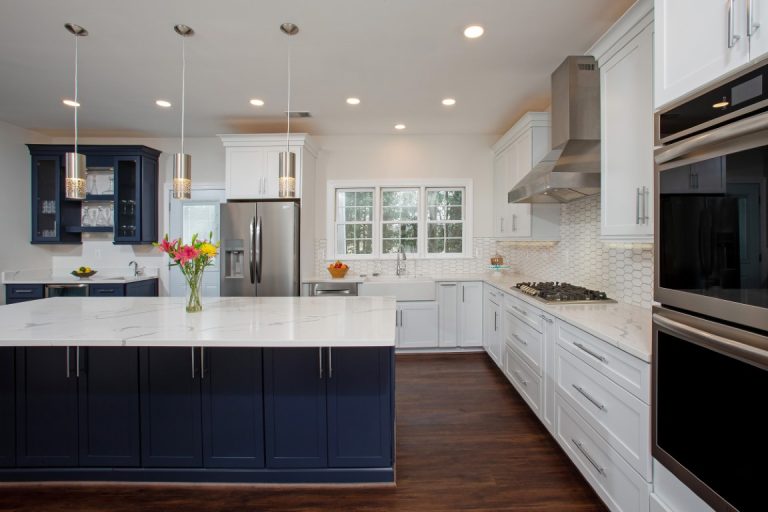 Modern kitchen with white cabinetry, dark blue island, stainless steel appliances, and hardwood flooring