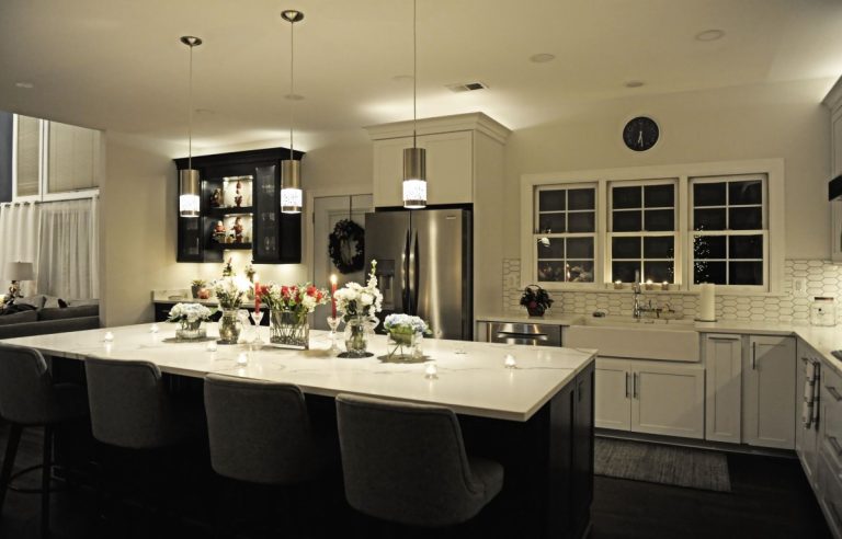 Modern kitchen with black island, white countertops, stainless steel appliances, and light wood cabinetry