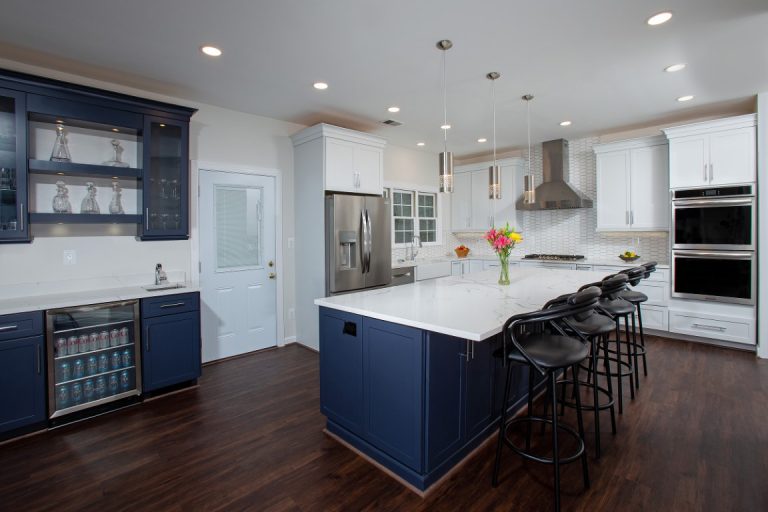 Modern kitchen with dark blue cabinetry, white countertops, stainless steel appliances, and island seating