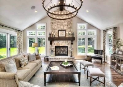 Bright sunroom with vaulted ceiling, fireplace, comfortable seating, and multiple windows overlooking green lawn