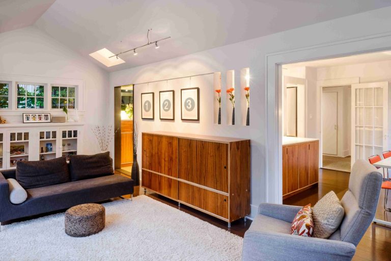 Modern home addition with open living area, wood cabinetry, blue seating, and skylights