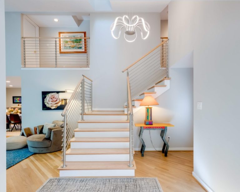 Modern staircase with wooden steps and metal railings in bright entryway with hardwood floors and contemporary decor