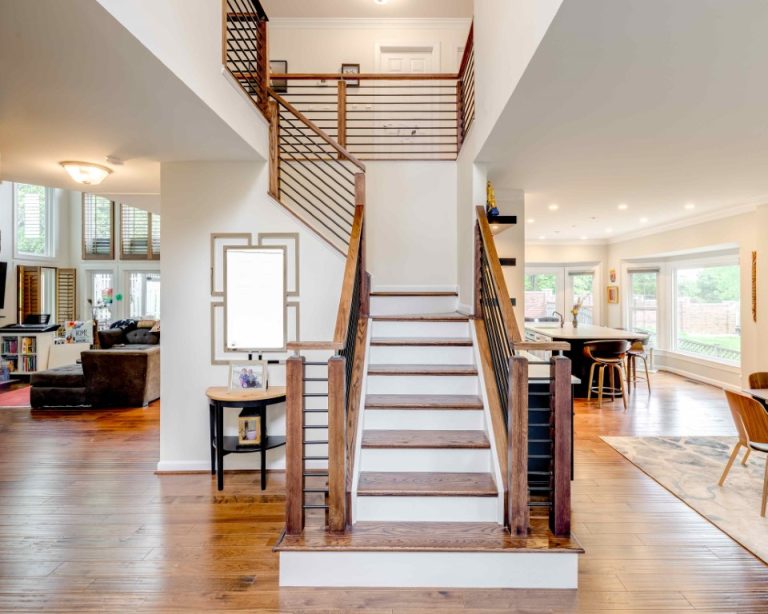 Modern staircase with wooden railings and white steps in an open-concept home with hardwood floors
