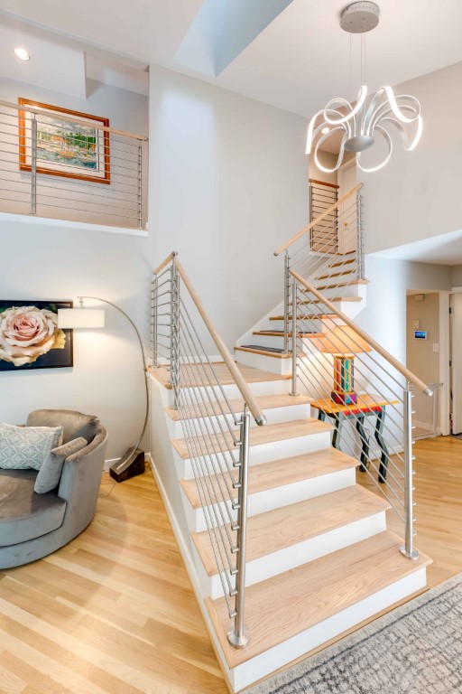 Modern staircase with wooden steps and metal railings in a bright, open-plan home interior with hardwood flooring
