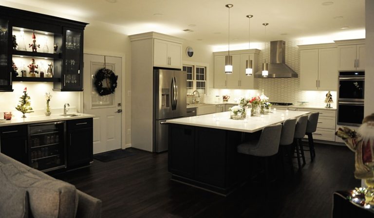 Modern kitchen with black and cream cabinetry, stainless steel appliances, white countertops, and black flooring