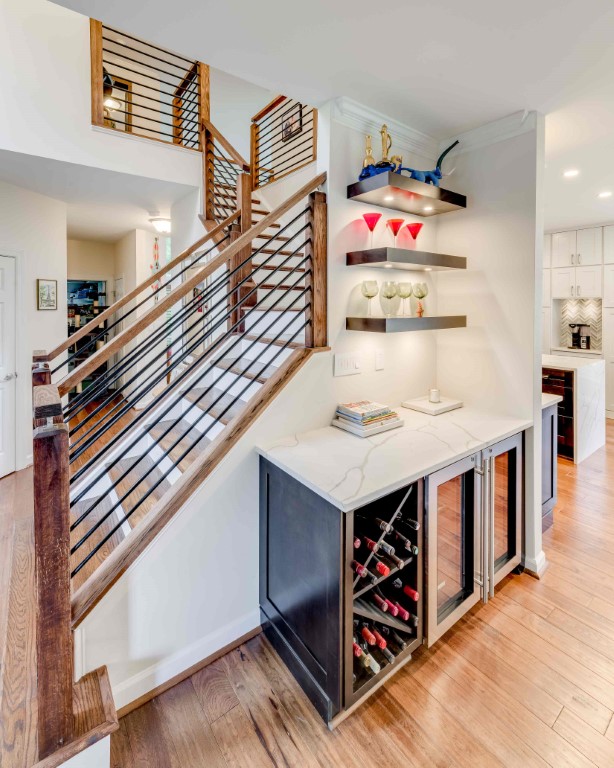 Modern kitchen with wooden stairs, metal railing, wine storage, and open shelving in a contemporary home