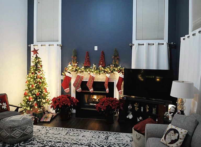 Festive Christmas living room with decorated tree, fireplace mantel, garland, and holiday decorations