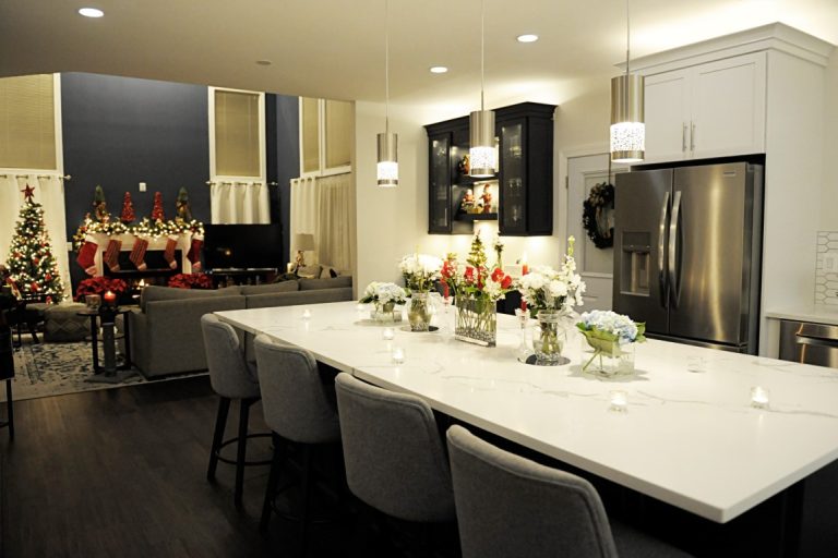 Modern kitchen and dining area with white countertops, stainless steel appliances, and holiday decorations