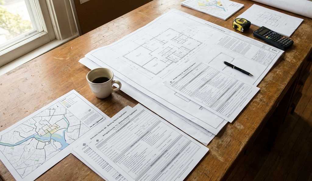 Arlington County permit application documents and construction plans on desk for ADU project review